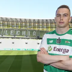 Piłkarz Lechii Gdańsk, gajos w zielono-białej koszulce, stoi na tle stadionu.