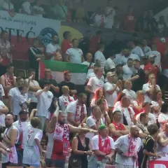 Tłum kibiców w biało-czerwonych barwach, z flagami i szalikami. Widać transparent z napisem "NOTEĆ". Atmosfera przypomina mecz, gdzie Polska rywalizuje z Izraelem.