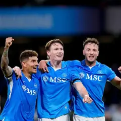 Trzech piłkarzy Napoli świętuje zwycięstwo nad Hellas Verona. Radość na twarzach i uniesione pięści świadczą o dobrych rankingach.