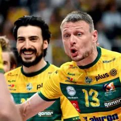 Dwóch zawodników w żółtych koszulkach, jeden uśmiechnięty, drugi krzyczy. Byli piłkarze reprezentacji Polski w akcji.