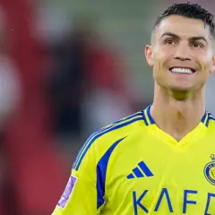 Uśmiechnięty Cristiano Ronaldo w żółtej koszulce swojego nowego klubu Al Nassr.