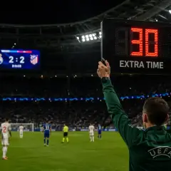 Sędzia podnosi tablicę z napisem "EXTRA TIME" i cyfrą "30", wskazując, ile trwa dogrywka w piłce nożnej. Wynik na tablicy to 2:2.