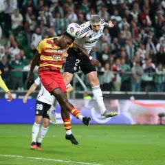 Piłkarze walczą o piłkę w powietrzu. W tle kibice, a na boisku emocje jak przy największych ekstraklasa transfery.