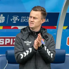 Trener z PKO BP Ekstraklasa w TVP, kiedy? Mężczyzna w kurtce z logo "hummel" klaszcze na ławce rezerwowych.