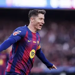 Piłkarz Robert Lewandowski w koszulce FC Barcelony świętuje bramkę na tle trybun.