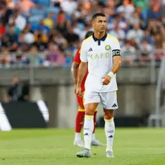 Piłkarz Cristiano Ronaldo na boisku, w białej koszulce z żółtymi detalami. Ile goli strzelił Ronaldo? To pytanie nurtuje fanów.