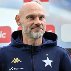 Łysy mężczyzna z siwą brodą, trener Wisły Kraków, w granatowej bluzie z kapturem z logo klubu.