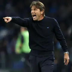 Antonio Conte, znany z taktyki catenaccio, krzyczy i wskazuje palcem, instruując zawodników na boisku.