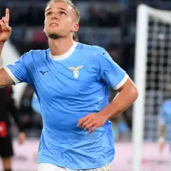 Piłkarz Lazio w błękitnej koszulce z uniesionym palcem, radośnie świętuje bramkę w meczu z A.C. Milan.