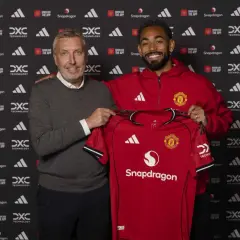Dwóch mężczyzn prezentuje czerwoną koszulkę Manchester United. To ważny moment w kontekście manchester united transfery.
