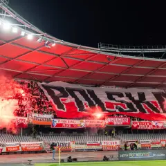 Tłum ultrasi na stadionie, odpalone race i ogromny transparent "POLSKA".