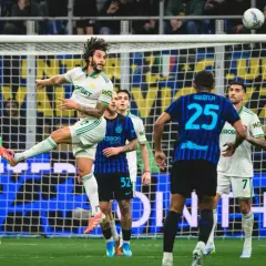 Piłkarz Interu Mediolan w akcji podczas meczu z AS Roma. Piłka w powietrzu, zawodnicy walczą o pozycję.