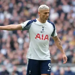 Piłkarz Tottenhamu z blond włosami w białej koszulce z logo AIA na tle trybun.