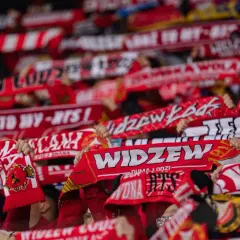 Tłum kibiców Widzewa Łódź z szalikami. Fani świętują, a na szalikach widnieją napisy "Widzew", "Łódź to my" i rok 1910. To symbol ich dumy i wsparcia dla klubu, który zawsze budzi emocje, zwłaszcza podczas ważnych widzew łódź transfery.