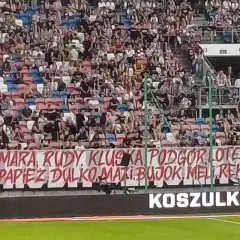 Tłum kibiców na trybunach, transparent z nazwiskami piłkarzy i hasłem "torcida".