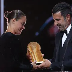 Piłkarz wręcza trofeum złota piłka kobiet.