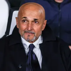 Łysy mężczyzna z brodą, ubrany w białą koszulę i granatowy krawat, w ciemnym płaszczu. To trener Juventusu, wpatrzony w dal.