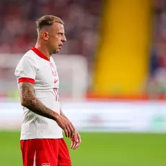 Piłkarz Kamil Grosicki w białej koszulce i czerwonych spodenkach, z tatuażami na ramieniu. Jego majątek budowany latami na boisku.