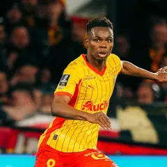 Piłkarz RC Lens w żółto-czerwonej koszulce biegnie po boisku, gotowy do akcji przeciwko Stade Rennais.