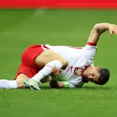 Robert Lewandowski leży na trawie, trzymając się za nogę. Wygląda na to, że to poważna lewandowski kontuzja.