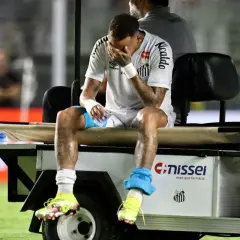 Neymar siedzi na wózku golfowym, zakrywając twarz dłońmi. Jego kontuzja jest widoczna na nogach.
