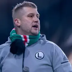 Staruch z Legii w szaliku klubowym, z mikrofonem przed ustami, gotowy do przemowy.