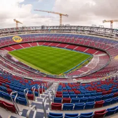 Stadion Camp Nou w trakcie przebudowy, z widocznymi dźwigami i częściowo pustymi trybunami.