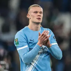 Erling Haaland w błękitnej koszulce Manchesteru City klaszcze, patrząc w bok.