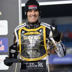 Uśmiechnięty żużlowiec Motor Lublin z pucharem, symbolizuje udane transfery i zwycięstwa.