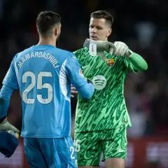 Dwóch bramkarzy, jeden w niebieskim z numerem 25, drugi w zielonej koszulce z logo Barcelony, rozmawia na boisku. Czyżby ten w zielonym był najlepszym bramkarzem na świecie?