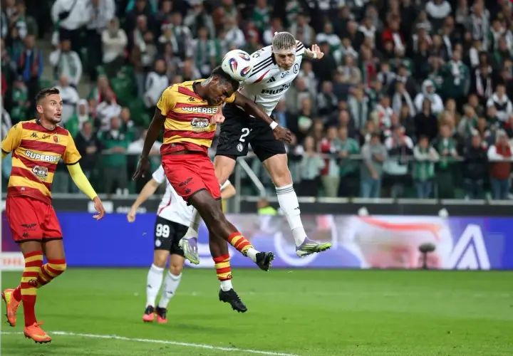 Piłkarze walczą o piłkę w powietrzu. W tle kibice, a na boisku emocje jak przy największych ekstraklasa transfery.