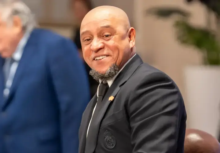 Uśmiechnięty Roberto Carlos w garniturze, z charakterystyczną brodą. Widać herb Realu Madryt. Roberto Carlos żyje i ma się dobrze!