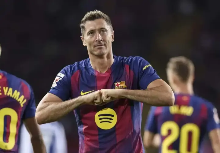 Robert Lewandowski w koszulce Barcelony, z gestem radości. Zastanawiasz się, ile zarabia Lewandowski na minutę?