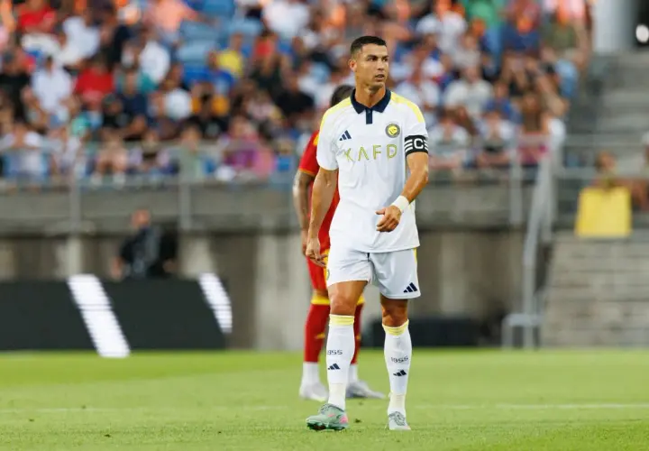 Piłkarz Cristiano Ronaldo na boisku, w białej koszulce z żółtymi detalami. Ile goli strzelił Ronaldo? To pytanie nurtuje fanów.
