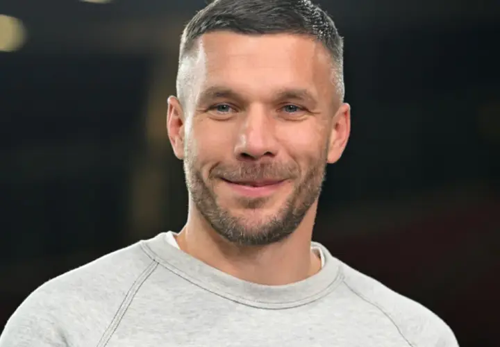 Uśmiechnięty Łukasz Podolski w szarej bluzie. Jego kariera piłkarska i biznesy budują imponujący lukas podolski majątek.