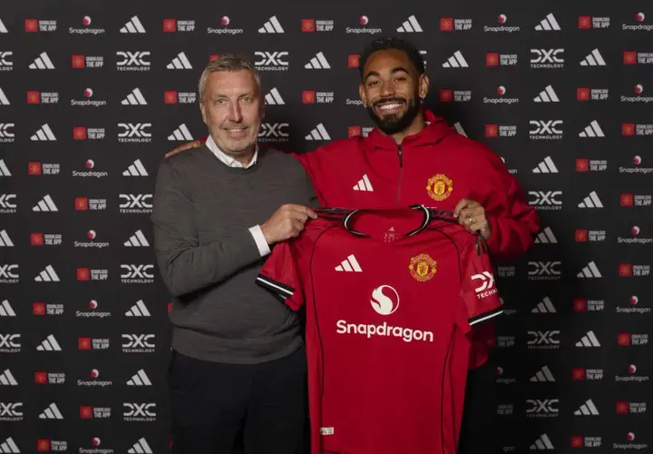 Dwóch mężczyzn prezentuje czerwoną koszulkę Manchester United. To ważny moment w kontekście manchester united transfery.