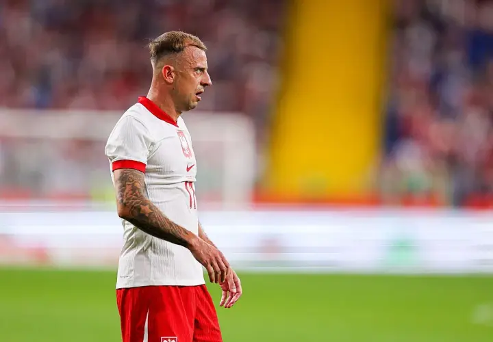 Piłkarz Kamil Grosicki w białej koszulce i czerwonych spodenkach, z tatuażami na ramieniu. Jego majątek budowany latami na boisku.