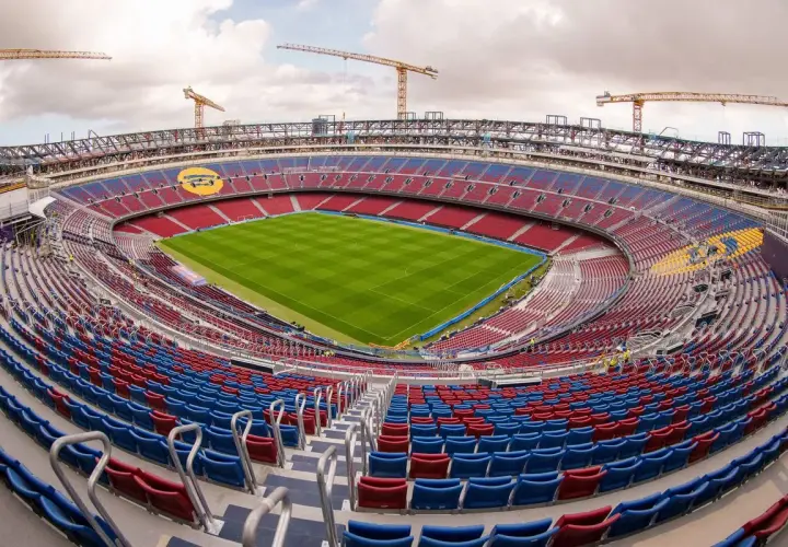 Stadion Camp Nou w trakcie przebudowy, z widocznymi dźwigami i częściowo pustymi trybunami.