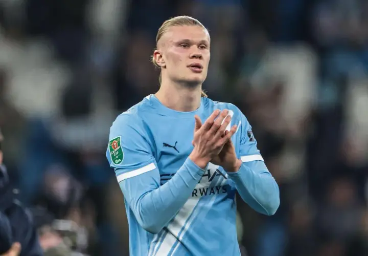 Erling Haaland w błękitnej koszulce Manchesteru City klaszcze, patrząc w bok.
