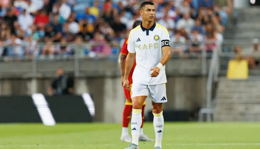 Piłkarz Cristiano Ronaldo na boisku, w białej koszulce z żółtymi detalami. Ile goli strzelił Ronaldo? To pytanie nurtuje fanów.