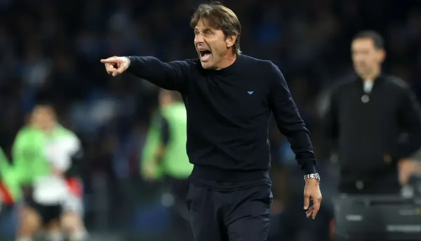 Antonio Conte, znany z taktyki catenaccio, krzyczy i wskazuje palcem, instruując zawodników na boisku.