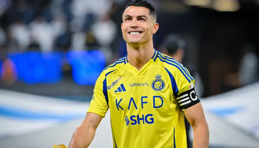 Uśmiechnięty Cristiano Ronaldo w żółtej koszulce Al Nassr. W jakim klubie gra Ronaldo? W Al Nassr!