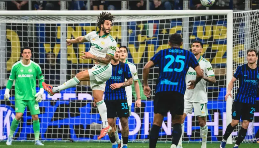 Piłkarz Interu Mediolan w akcji podczas meczu z AS Roma. Piłka w powietrzu, zawodnicy walczą o pozycję.