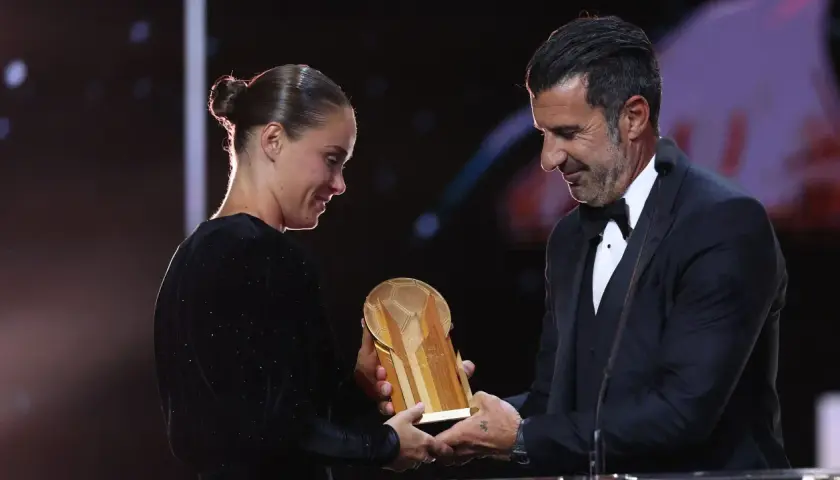 Piłkarz wręcza trofeum złota piłka kobiet.