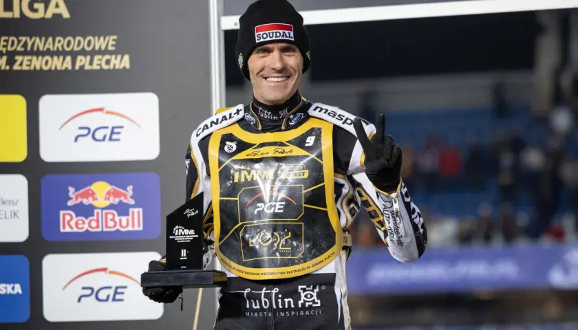 Uśmiechnięty żużlowiec Motor Lublin z pucharem, symbolizuje udane transfery i zwycięstwa.
