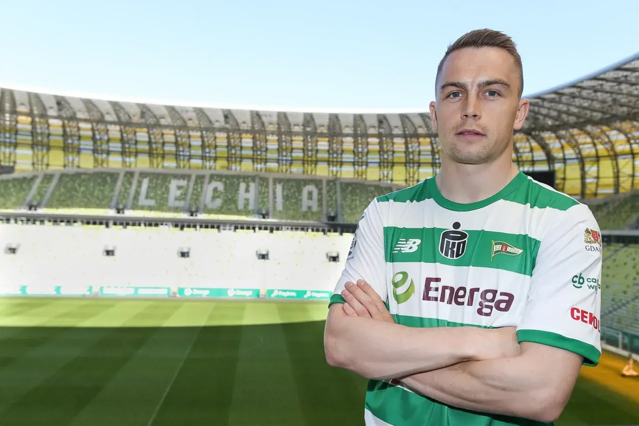Piłkarz Lechii Gdańsk, gajos w zielono-białej koszulce, stoi na tle stadionu.