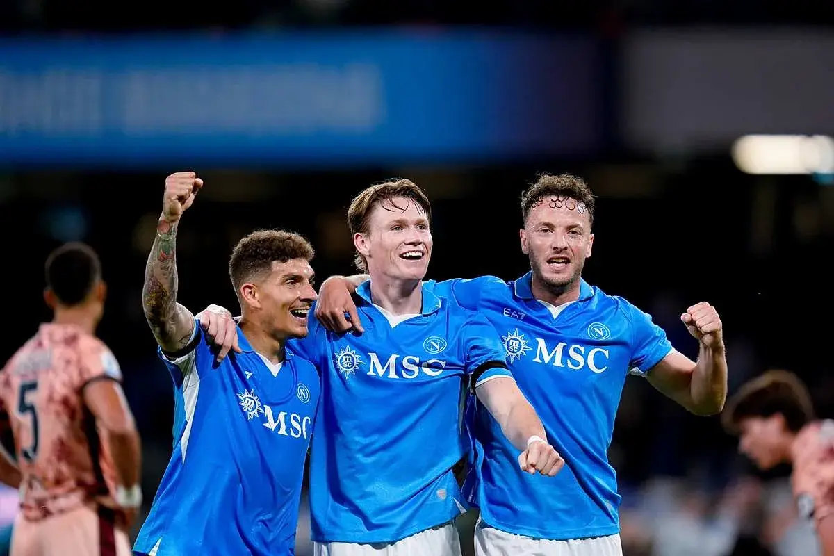 Trzech piłkarzy Napoli świętuje zwycięstwo nad Hellas Verona. Radość na twarzach i uniesione pięści świadczą o dobrych rankingach.