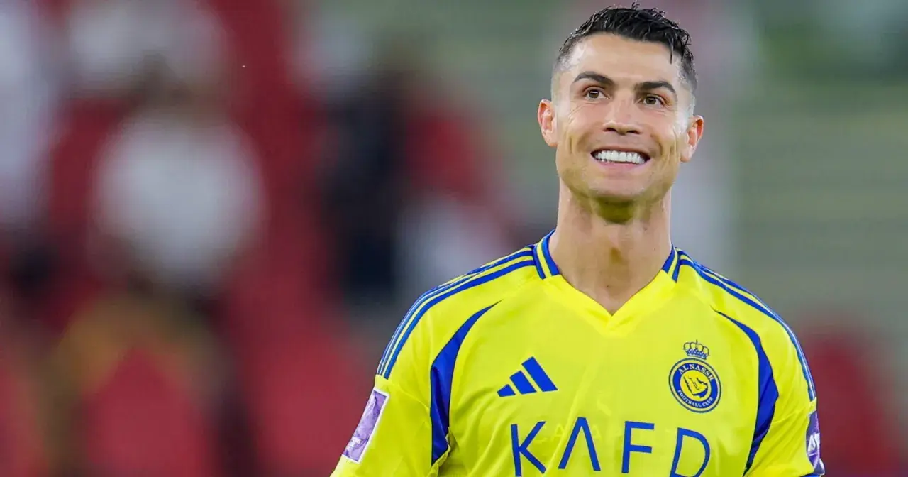 Uśmiechnięty Cristiano Ronaldo w żółtej koszulce swojego nowego klubu Al Nassr.