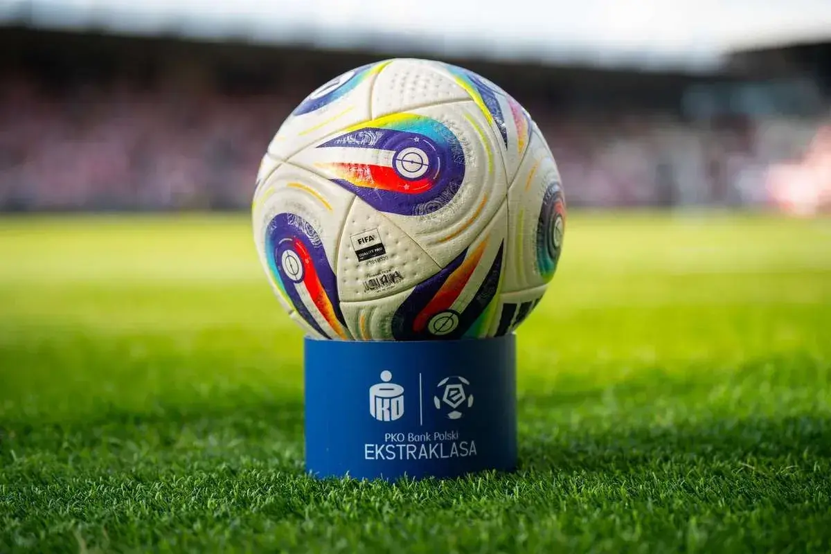 Piłka PKO Bank Polski Ekstraklasa na niebieskim postumencie. Czas odmierza, ile kolejek do końca sezonu.