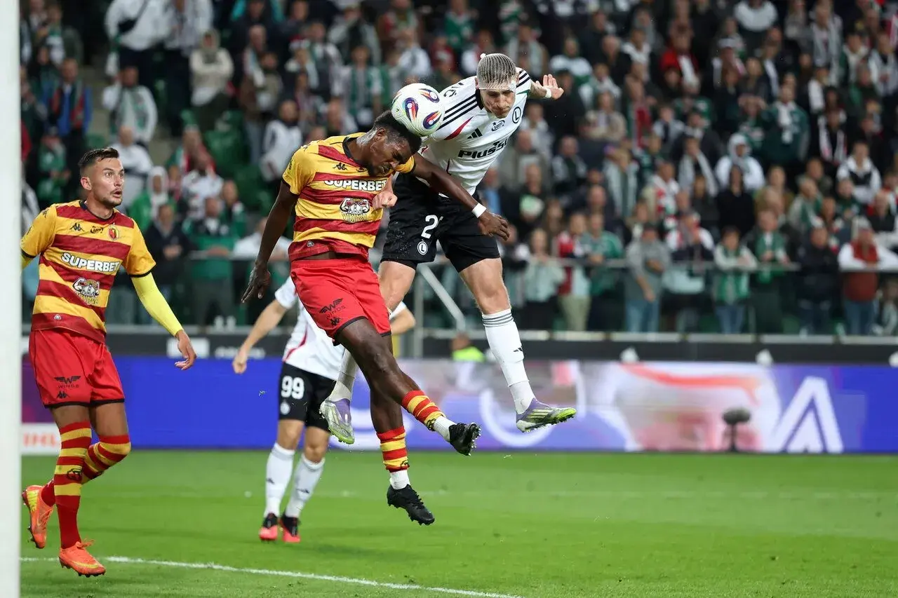 Piłkarze walczą o piłkę w powietrzu. W tle kibice, a na boisku emocje jak przy największych ekstraklasa transfery.